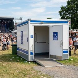 Large ADA-compliant portable restroom unit at an outdoor festival.